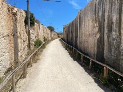 Picture of a a long empty pathway of dirt between walls of stone. 