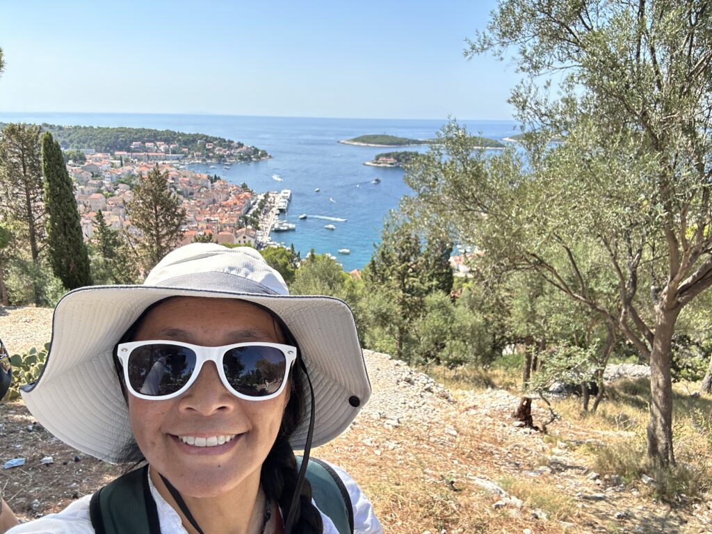 Selfie of Dragon on the summit of a hike with the ocean and city in the background.