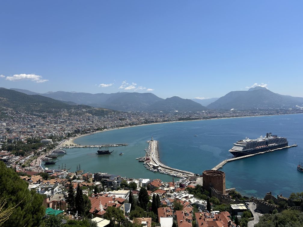 A landscape photo of the beauty of Alanya, Turkiye from high up the hillside with the Red Tower and the cruise ship down below.