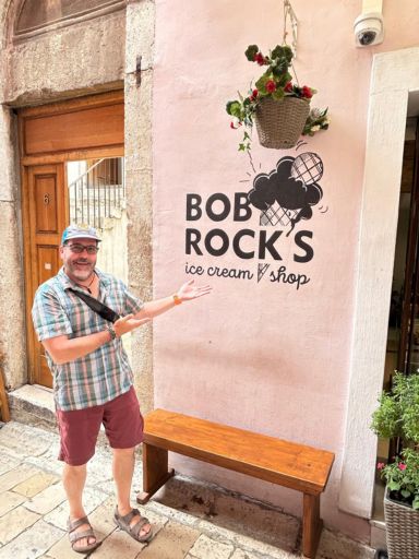 Dog standing by the sign for Bob Rock's Ice Cream Shop in Zadar, Croatia