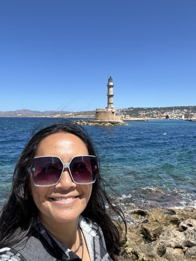 Dragon selfie at the Chania harbor with the old Venetian lighthouse behind her.